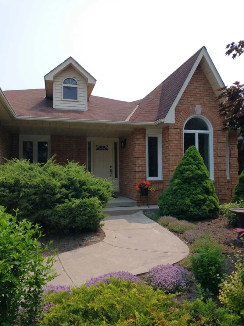 Brick bungalow with new white windows, an arched window and a front door, installed by Panorama Windows & Doors Brick bungalow with new white windows, an arched window and a front door